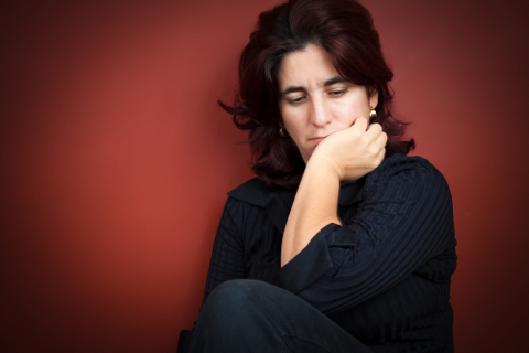 Beautiful hispanic woman with a very sad expression on a dark red background
